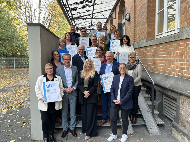Vertreter*innen der ausgezeichneten Unternehme stehen auf einer Treppe vor dem Bernardbau Offenbach und halten ihre Urkunde mit dem UFF-Siegel in der Hand